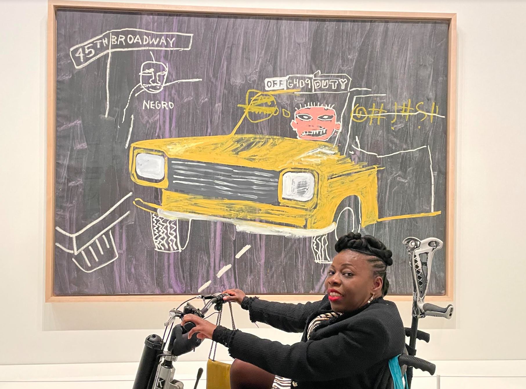Deza une femme noir handicapée repose dans son fauteuil roulant devant une œuvre d'art, émanant une présence forte et contemplative. les contrastes de sa posture et de l'œuvre captivent l'attention. 